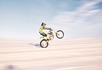 Bike, speed and balance with a sports man riding a vehicle in the desert for adventure or adrenaline. Motorcycle, training and motion blur with an athlete outdoor in nature for freedom or power