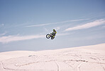 Bike, sky and jump with a man in the desert riding a vehicle for adventure or adrenaline. Motorcycle, speed and training on sand with an athlete outdoor in nature for freedom or extreme sports