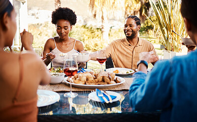 Group of friends at table, eating in garden and happy event with diversity, food and wine bonding together. Outdoor dinner, men and women at lunch, people at party with drinks in backyard in summer.