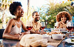 Friends at lunch, conversation in garden and happy event with diversity, food and wine, outdoor bonding together. Dinner party, men and women at table, people eating and talking in backyard in summer