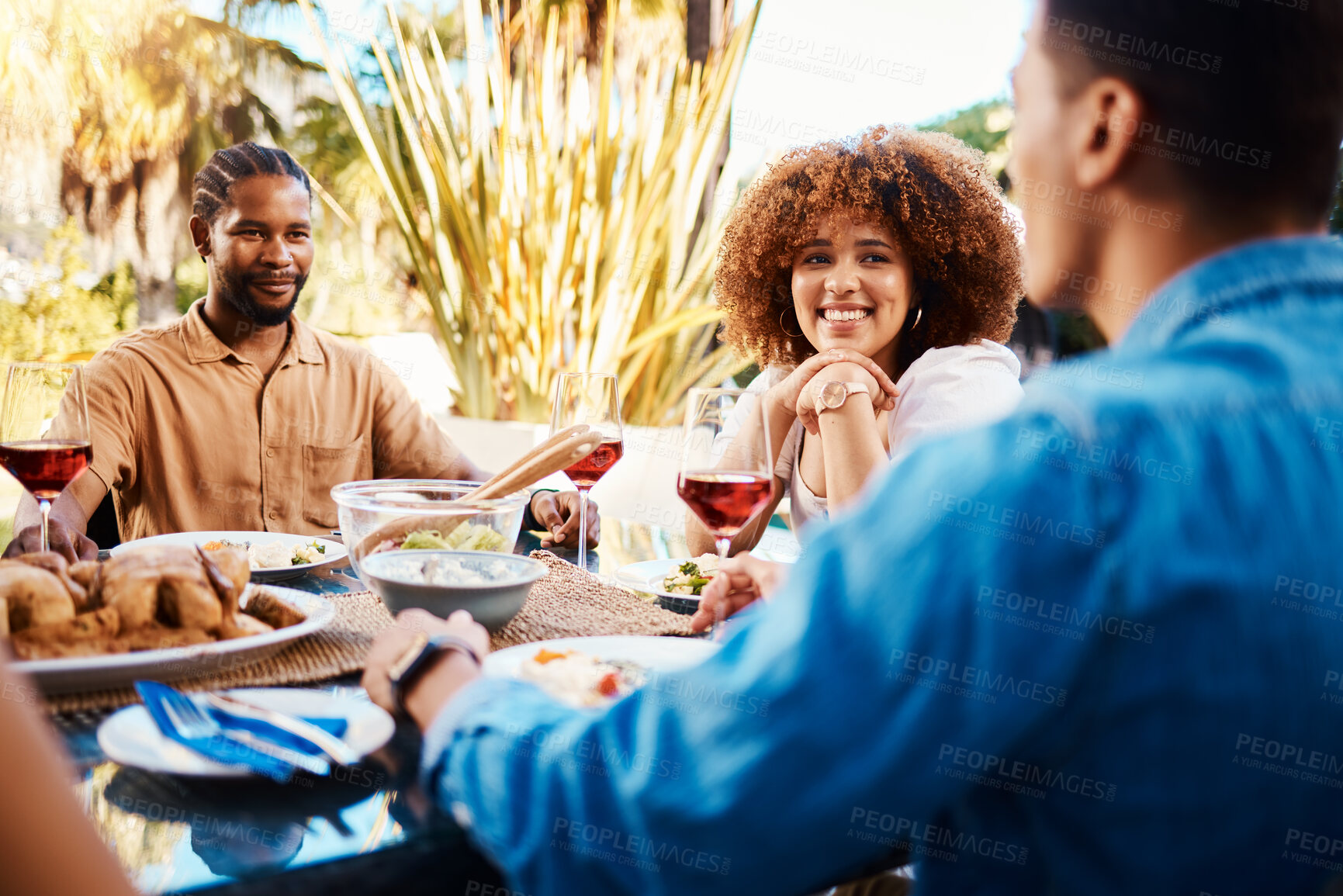 Buy stock photo Happy, friends and lunch in a garden with conversation, eating and bonding at a table. Smile, laughing and diversity of a woman and men in a backyard with food, conversation or dinner together