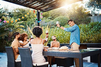 Buy stock photo Cheers, group of friends at dinner in garden at party and celebration with diversity, food and wine at outdoor party. Glass toast, men and women at table, fun people with drinks in backyard together.