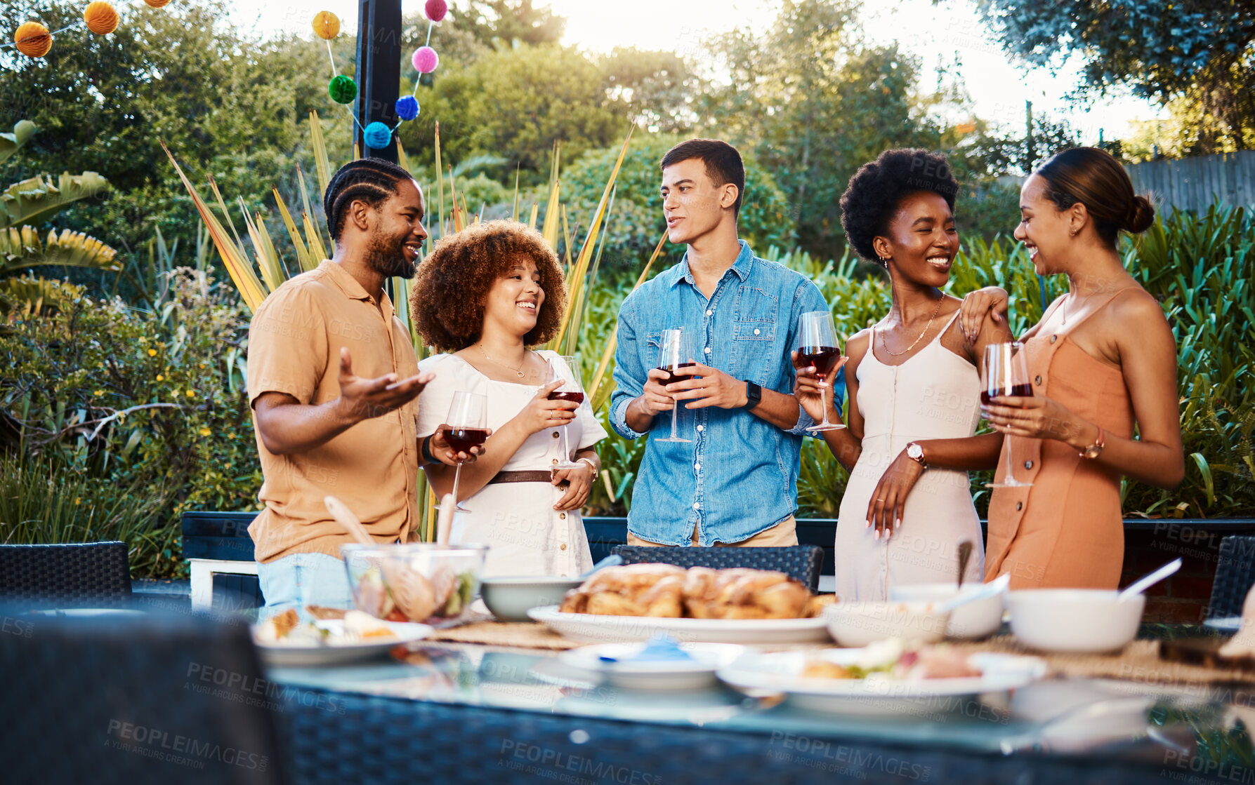 Buy stock photo Talk, friends at dinner in garden at party and celebration with diversity, food and wine at outdoor event. Conversation, men and women at table for lunch, fun people with drinks in backyard together.