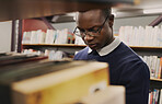 University, student and black man in a library reading and learning on campus for knowledge and education in college. Smart, clever and person doing research with books on a shelf for an exam