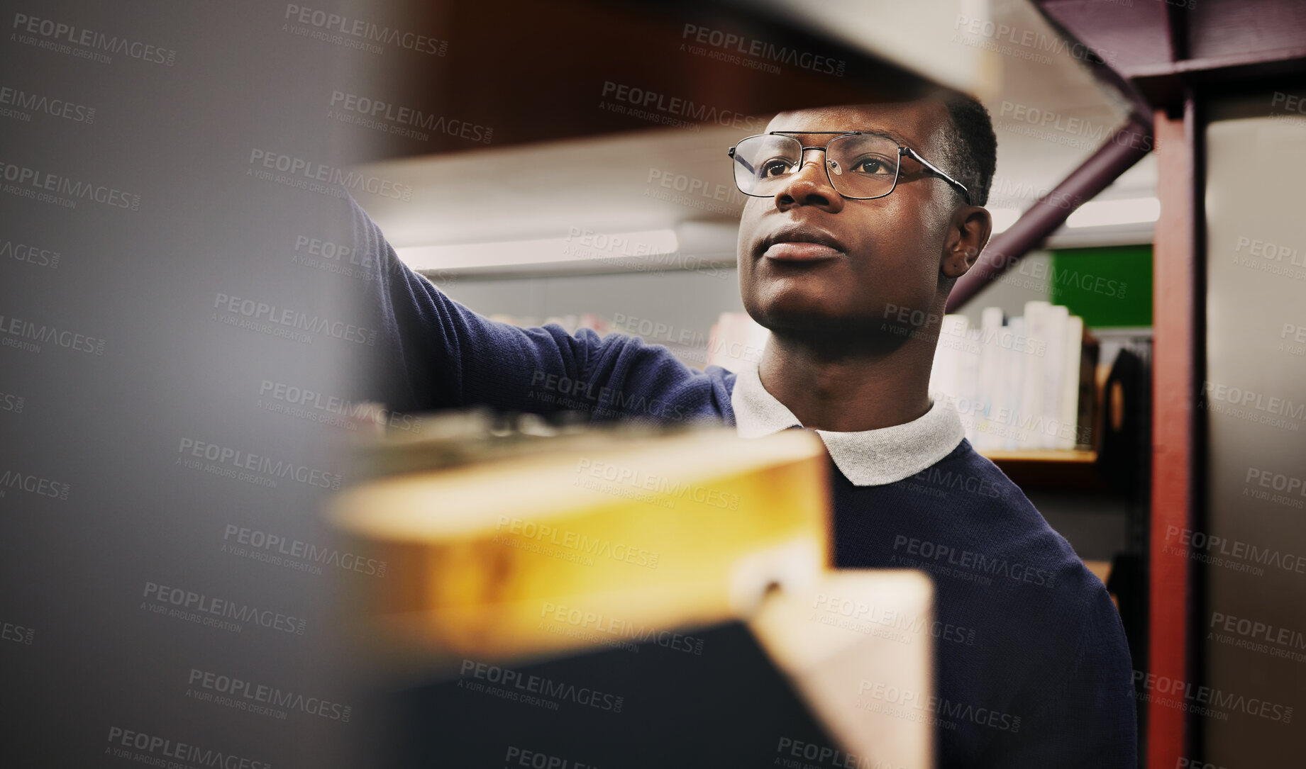 Buy stock photo Knowledge, research and black man in a library search and learning on campus for studying and education in college. Smart, clever and young person in an academy with books on a shelf for an exam