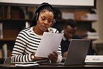 Woman, documents and headphones in library for research, studying and computer research or planning in university. African student reading paper, listening to music and laptop for focus and learning