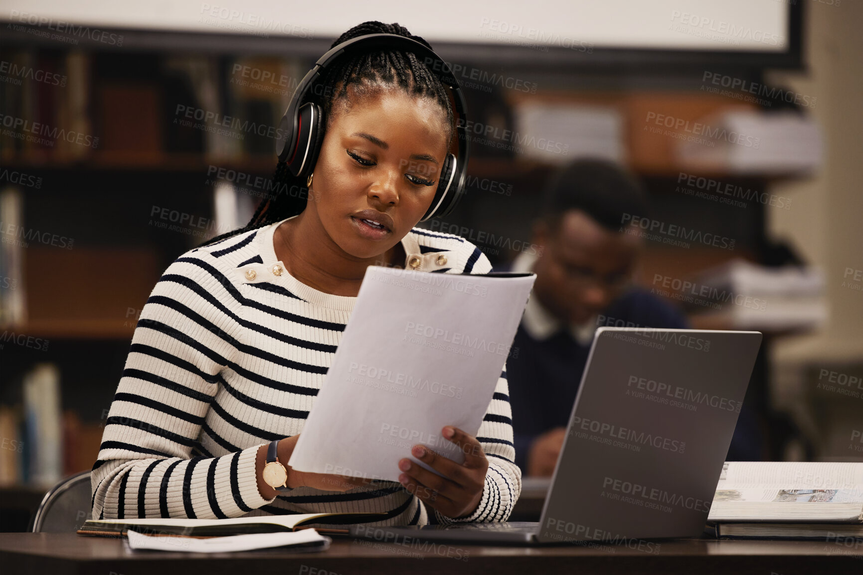 Buy stock photo Woman, documents and headphones in library for research, studying and computer research or planning in university. African student reading paper, listening to music and laptop for focus and learning