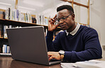 Man, student and thinking on laptop in library for studying, university research or headache and stress of debt or results. Young and confused african person on computer for education FAQ or question