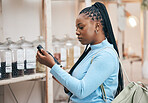 Woman, shopping and reading ingredient bottle in local grocery store for healthy food, nutrition and wellness product sales. Thinking, African customer and salad dressing choice in retail supermarket