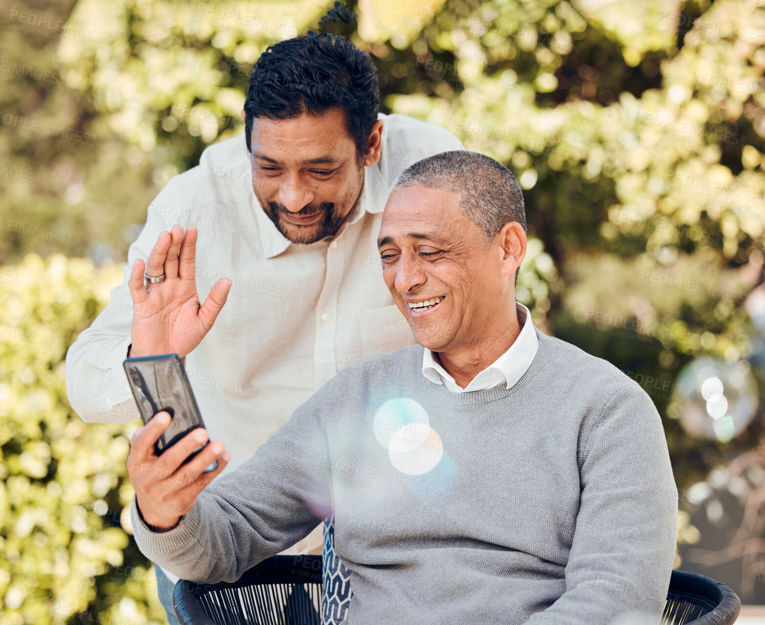 Buy stock photo Father, adult son and smartphone, video call and hello with communication while outdoor, happy and wave. Chat, talking and family, internet and men in the park, technology and using phone with app
