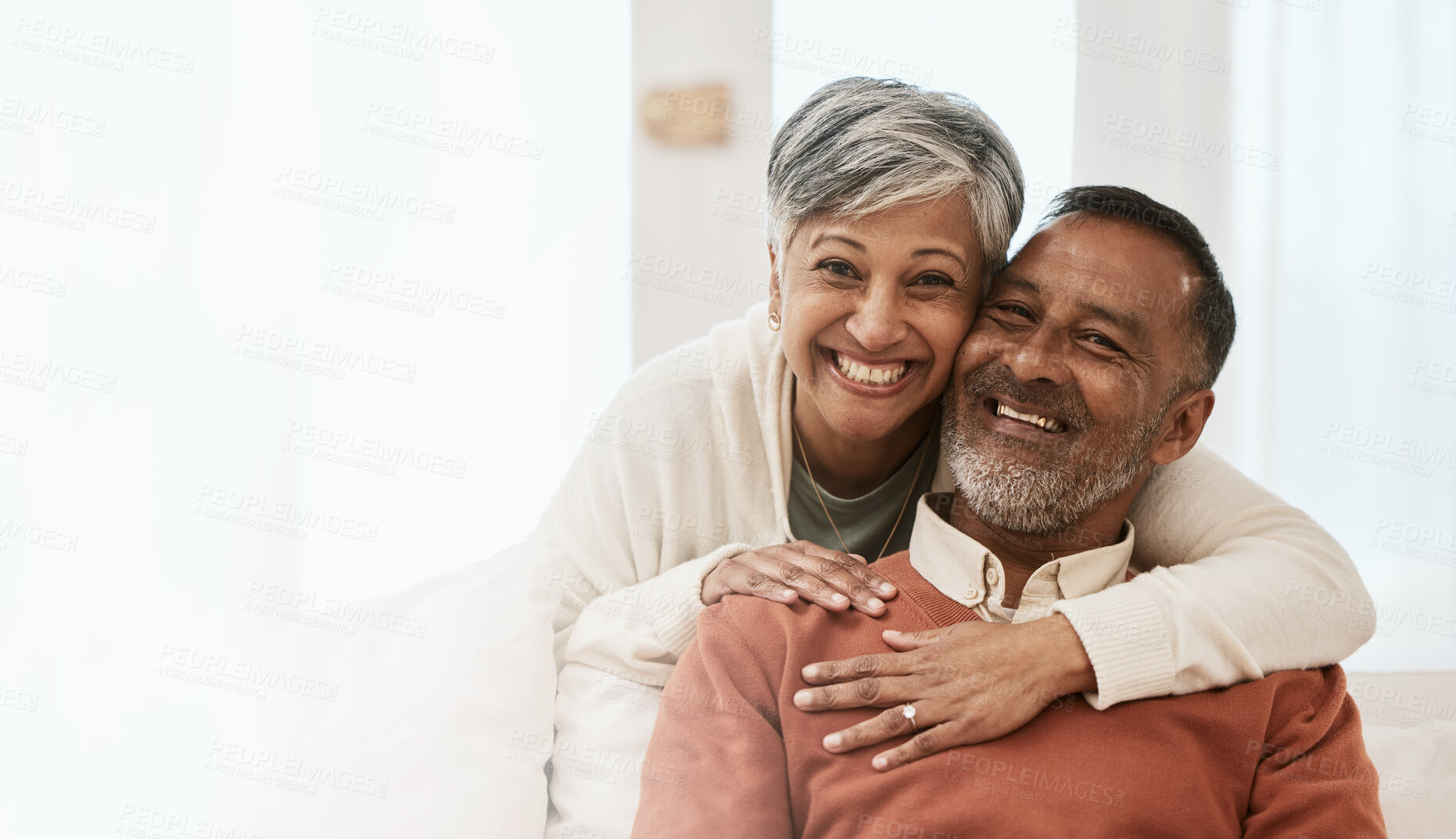 Buy stock photo Portrait, smile and senior couple in home living room, bonding together and hug on mockup space. Happy face, man and Indian woman in lounge for care, love or support in healthy relationship at house