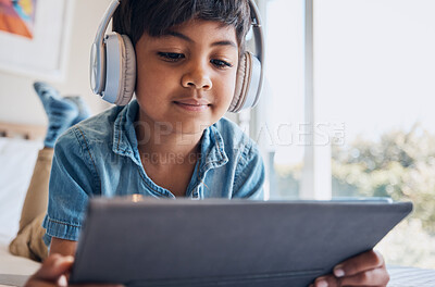 Buy stock photo Boy kid, tablet and headphones on bed, reading or idea with e learninng, movie and relax with web video. Male child, digital touchscreen and thinking in bedroom for audio, show and streaming in home