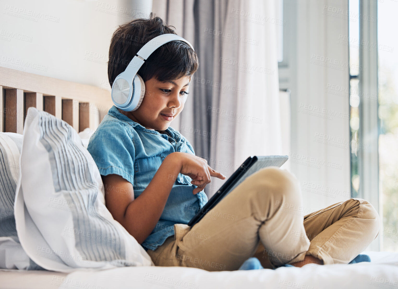 Buy stock photo Boy, kid and headphones with tablet on bed for online games, watching movies or play educational app. Happy child, digital technology or listening to multimedia, music or streaming cartoon in bedroom