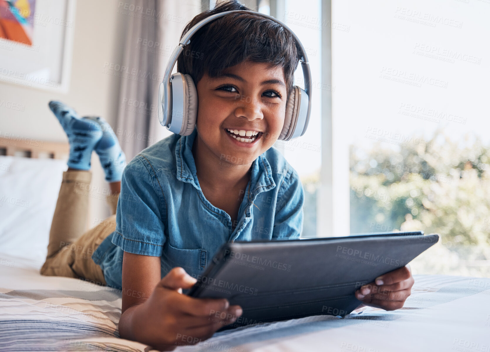 Buy stock photo Boy, tablet and headphones on bed, portrait or smile for streaming subscription, movie or video to relax. Male child, digital touchscreen and excited in bedroom with audio, show or elearning in home