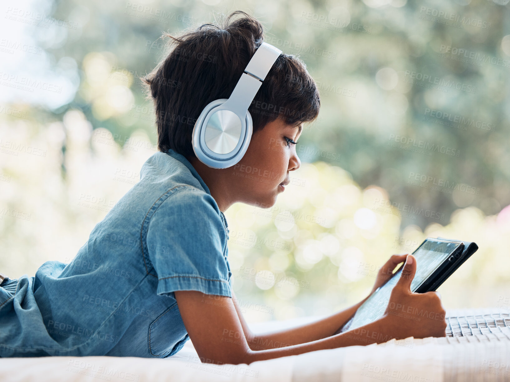 Buy stock photo Boy child, tablet and headphones on bed, reading or idea with e learninng, movie and web video to relax. Male child, digital touchscreen and thinking in bedroom for games, music and streaming in home