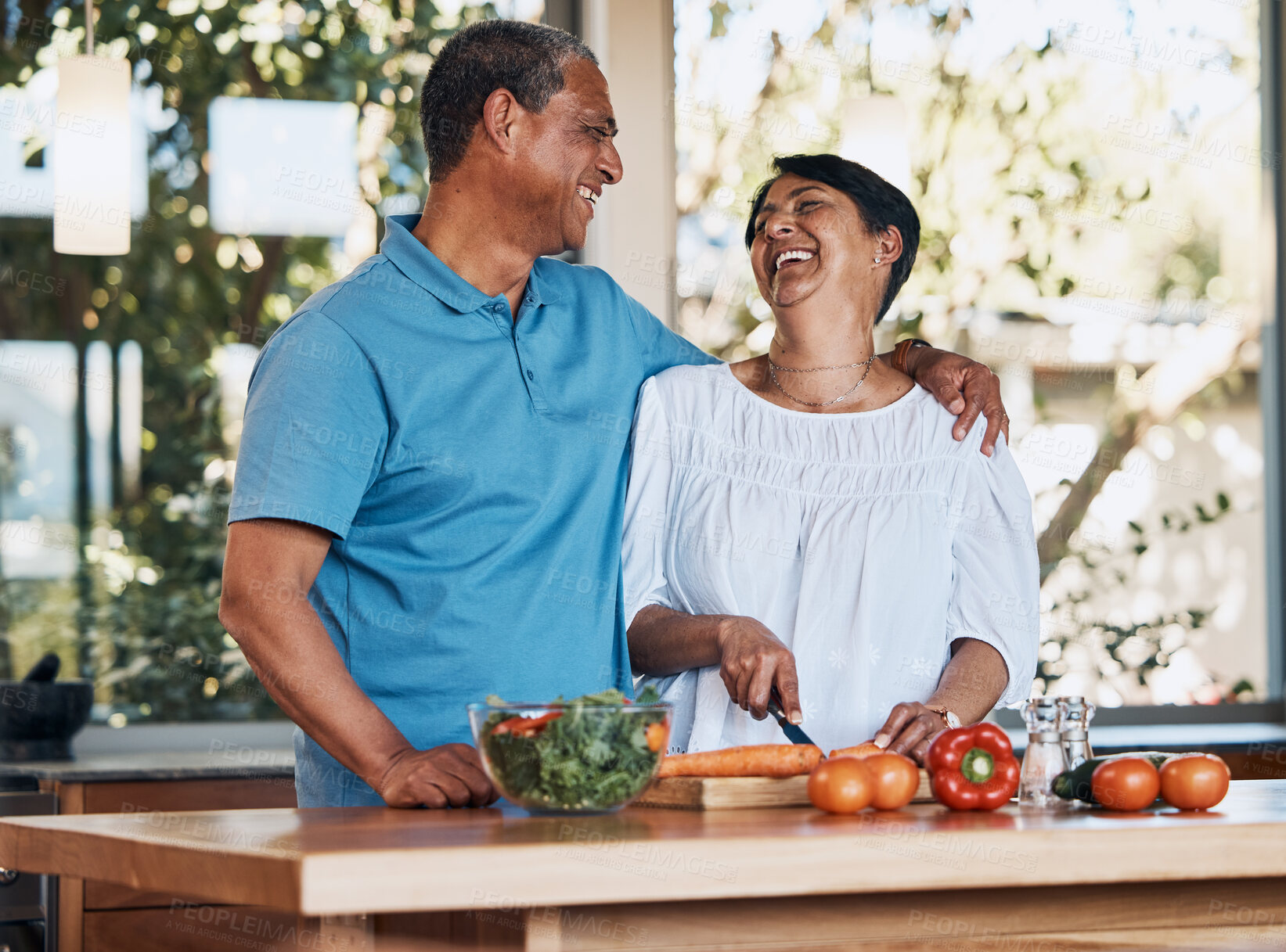 Buy stock photo Couple, love and laugh while cooking food, cutting carrot or prepare vegetables for salad at home. Happy man, mature woman and hug for funny conversation, making healthy lunch meal or diet for dinner