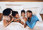 Family, funny and kids laughing in bed at home in the morning together with their happy parents. Relax, love or smile with a mother, father and children lying in a bedroom for weekend bonding