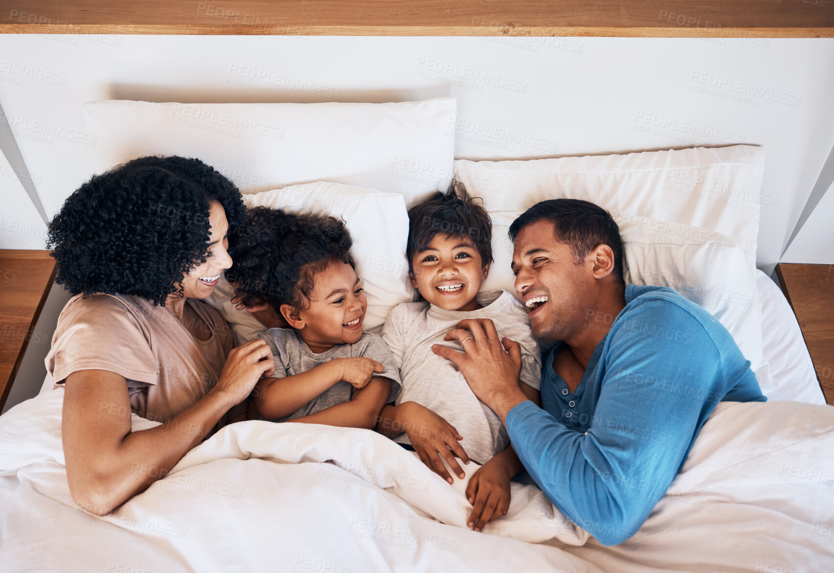 Buy stock photo Family, funny and kids laughing in bed at home in the morning together with their happy parents. Relax, love or smile with a mother, father and children in a bedroom for weekend bonding from above