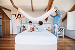 Blanket, fort and children on bed with parents for fun, play or hand game in their home. Bedroom, cover and kids with mother and father waking up, happy and weekend, day off or family time in house