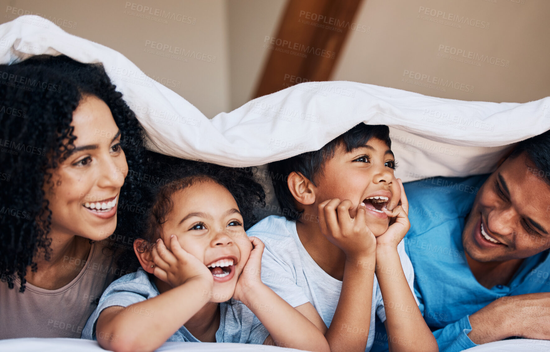 Buy stock photo Happy, smile and children with their parents by a blanket on a bed together for bonding or connection. Happiness, love and young family from Colombia relaxing in the room of their modern house.