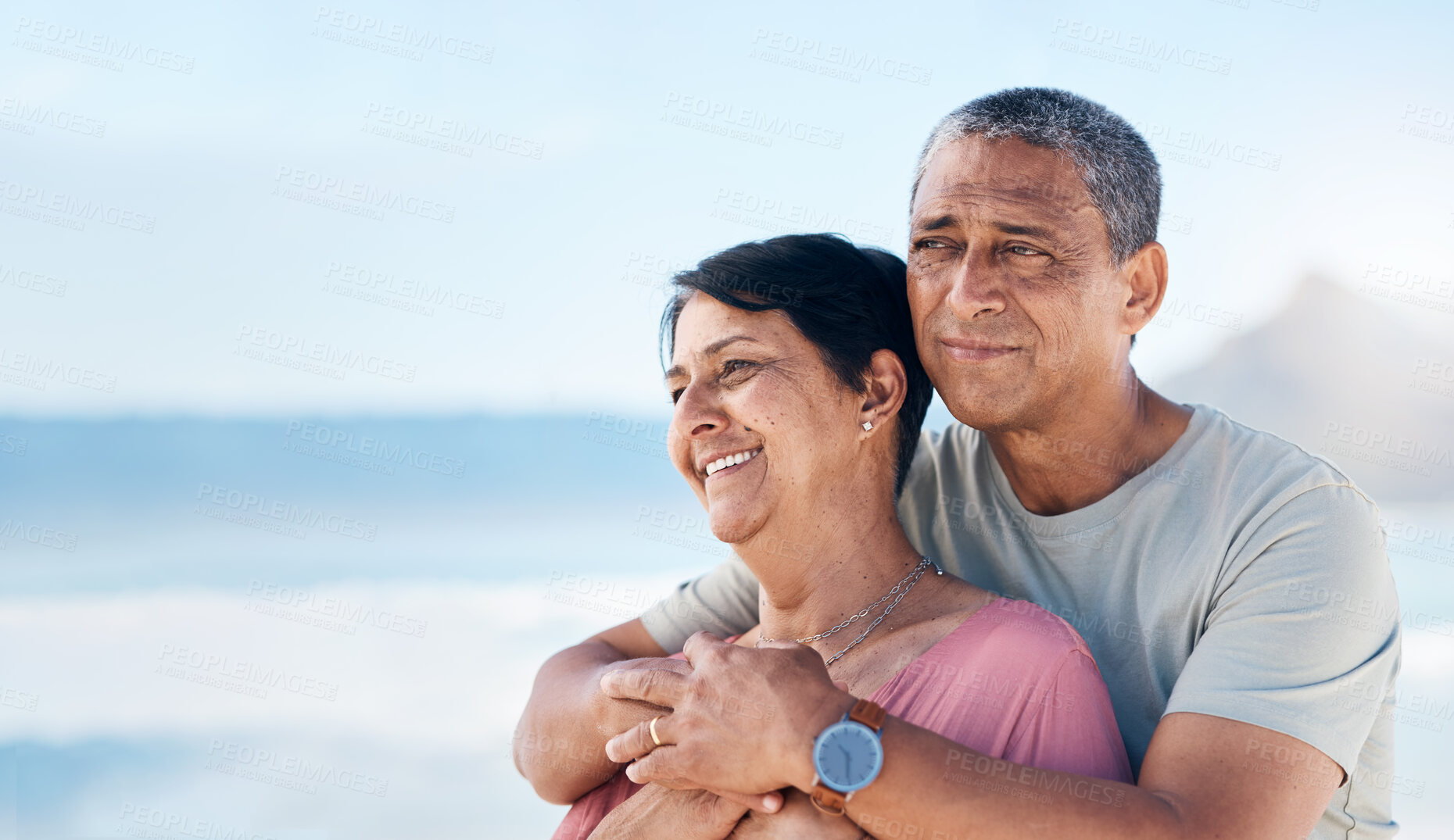 Buy stock photo Happy, mature couple and hug outdoor at beach with a smile, care and happiness together. Man and woman thinking of healthy marriage, commitment and freedom on a travel holiday with space in sky