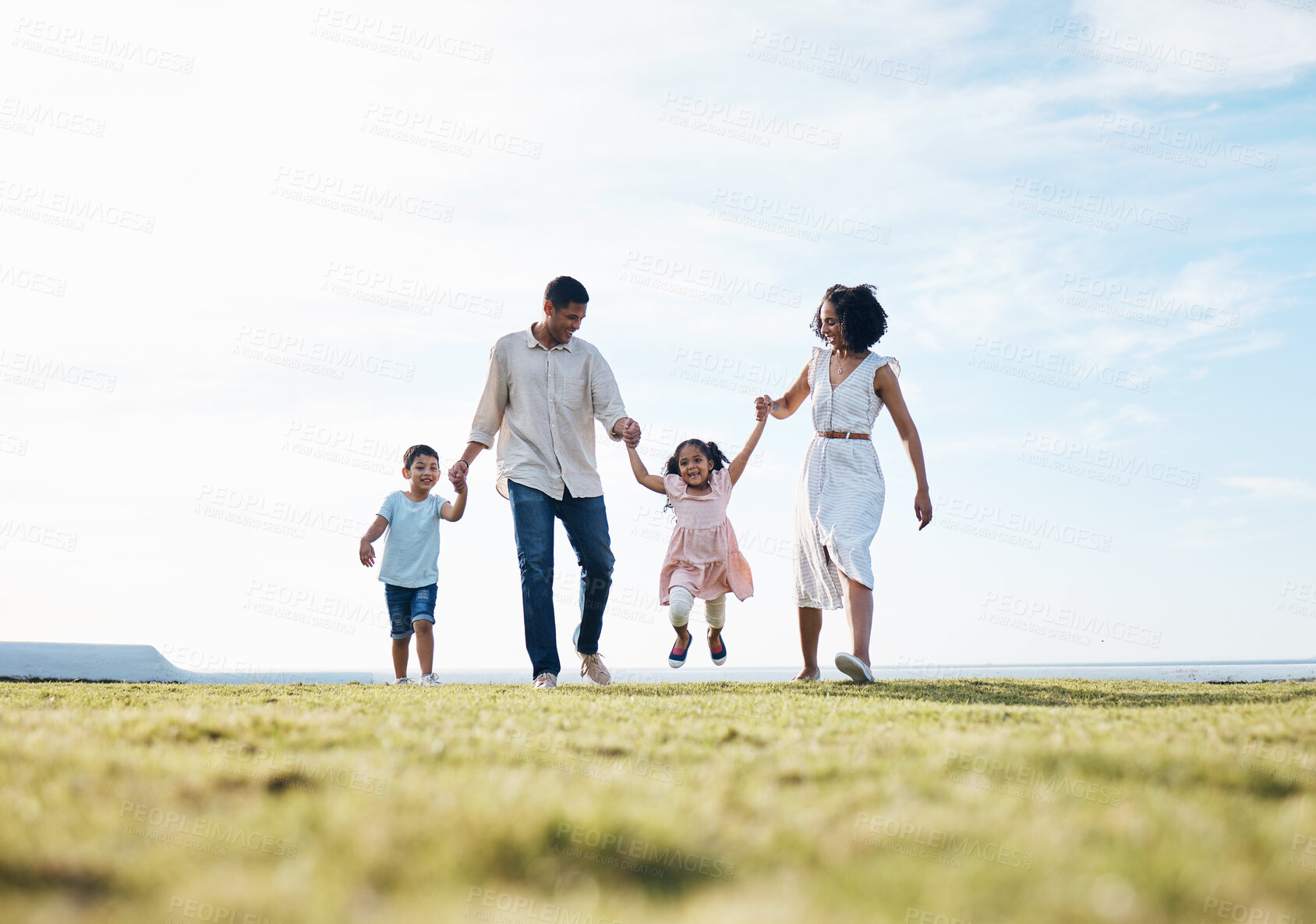 Buy stock photo Holding hands, family and outdoor at a park with love, care and happiness together in nature. Young man and woman or parents with children on walk, sky and playing on fun journey or travel holiday