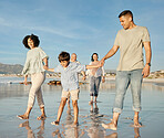 Love, kids and a family walking on the beach together for summer vacation or holiday in nature. Sky, freedom or travel with grandparents, parents and children outdoor for summer bonding by the ocean