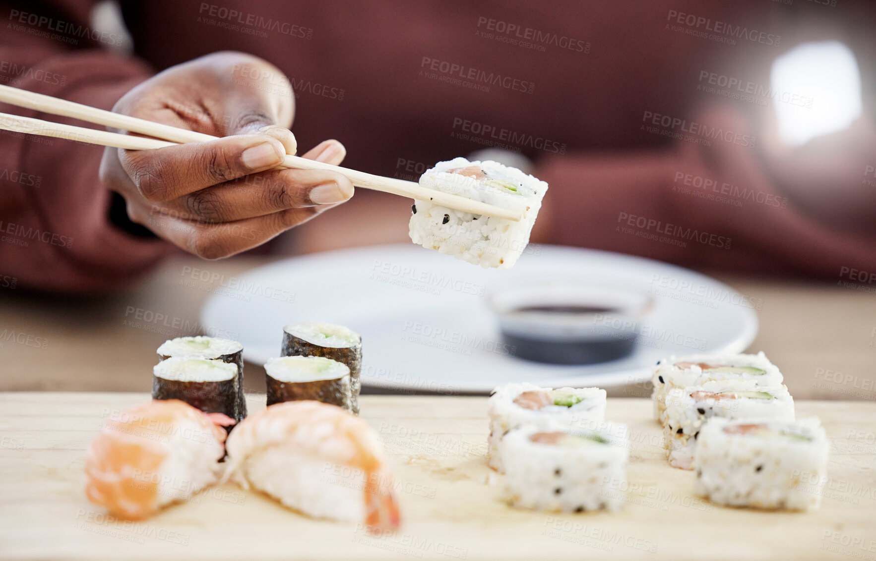 Buy stock photo Sushi, seafood and restaurant with hands of person in store for brunch, Japanese cuisine and menu. Fish, salmon and health with closeup of customer eating for nutrition, Asian diet and fine dining