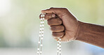 Rosary, person hand and prayer beads in a home with hop, christian praise and religion. Praying, necklace and worship in a house with hope, gratitude and spiritual guide for support and healing