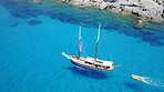 Boat, sailing in blue water and summer sun on ocean holiday, relax in freedom and nature. Yacht vacation, aerial of travel and tropical cruise on adventure to Greek island with sunshine, fun and sea.