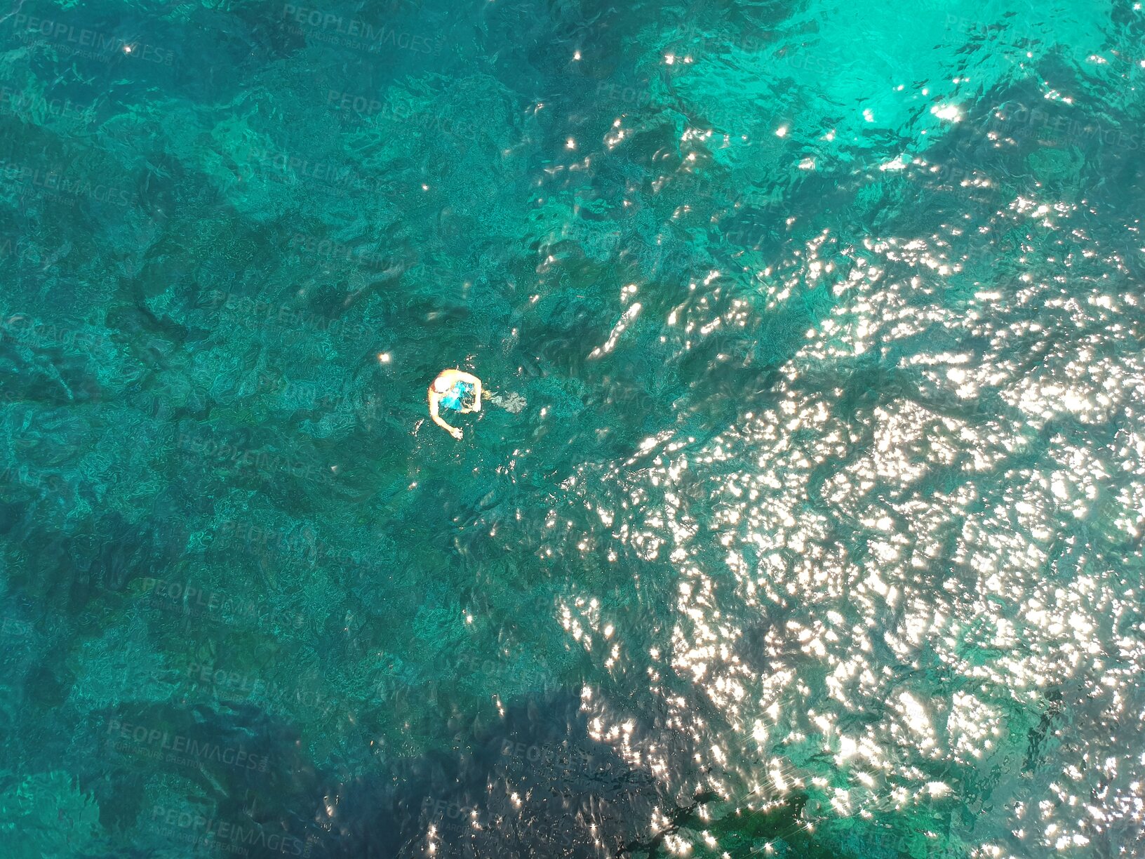 Buy stock photo Above, swimming and a person in the ocean in summer for a beach vacation, travel or relax in the water. Nature, sunshine and a man in the sea for stress relief, holiday or happy with a drone view