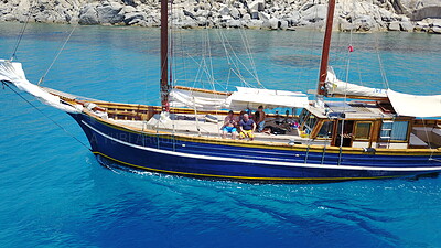 People on wooden boat, sailing in Greece and summer sun on ocean holiday, relax in freedom and nature. Yacht vacation, family travel and tropical cruise on sea adventure to Greek island on blue water