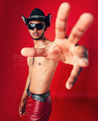 Buy stock photo Man, portrait and fashion with grunge in studio or red background with unique cowboy aesthetic and sunglasses. Gen z, style and model with pride and hand in photography, retro or western clothing