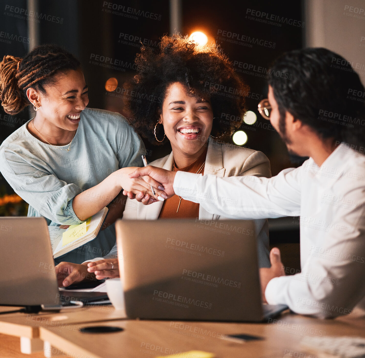 Buy stock photo Night, handshake and business people in discussion in office with partnership, deal or collaboration. Laptop, team and professional designers shaking hands for working overtime on creative project.