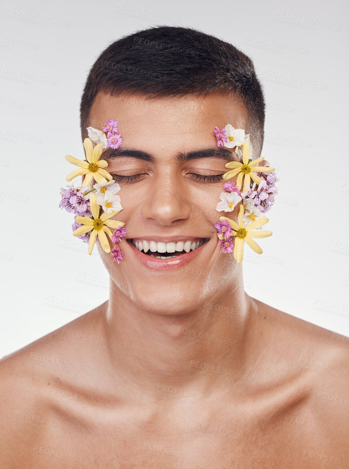 Buy stock photo Floral, face or happy man with flowers for beauty, natural cosmetics or wellness in studio on white background. Nature aesthetic, smile or model laughing at eco friendly skincare or spring art design