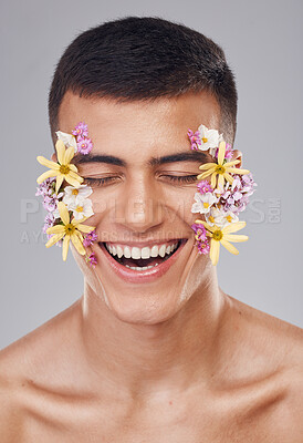 Buy stock photo Skincare, man and flowers on face in studio, eyes closed and natural cosmetics for art, makeup product and wellness. Spring, person and closeup of floral decoration for facial on gray background  