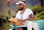 Summer, clipboard and a volleyball referee on the beach in a chair for authority, rules or regulations during a game. Health, documents or competition with a man refereeing a match in the day