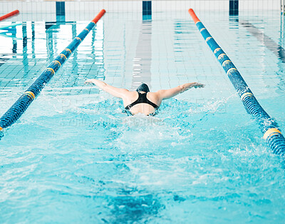 Sports, swimming pool and woman athlete training for a race, competition or tournament. Fitness, workout and back of female swimmer practicing a cardio water skill for exercise, speed or endurance.
