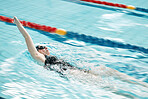 Sports, swimming pool and woman swimmer training for a race, competition or tournament. Fitness, workout and female athlete practicing back stroke cardio water skill for exercise, speed or endurance.