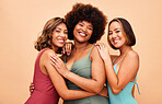 Diversity, bikini and portrait of women hug together happy for beach vacation isolated in a studio brown background. Smile, beauty and happy friends ready for summer holiday in swimsuit fashion 