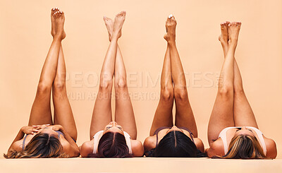 Buy stock photo Diversity, skincare and legs of women in studio for beauty, comparison or wellness on wall background. Difference, beauty and female friends relax in a line with feet up for glowing skin or treatment