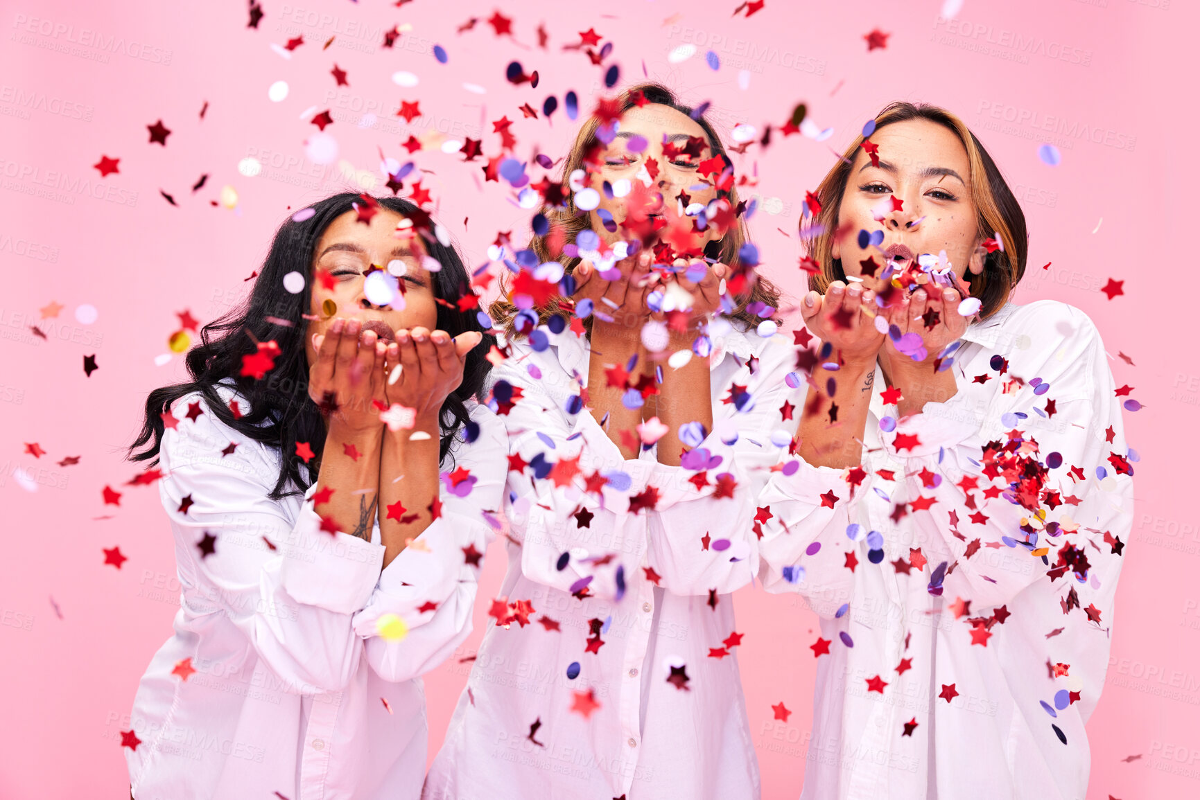 Buy stock photo Blow, friends and women in studio with confetti for clothing promotion, fashion sale and discount. Excited, diversity and female people on pink background for bonding, celebration and having fun