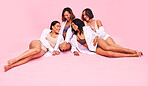 Happy, women friends and conversation with female confidence in group together in studio. Pink background, lying and ground with diversity, wellness and relax in underwear with fashion and style