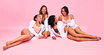 Happy, women friends and conversation in a studio with female confidence in group together. Pink background, lying and ground with diversity, wellness and relax in underwear with fashion and style