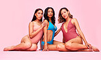 Beauty, swimwear and women in studio together, sitting with bikini and body positivity in portrait. Diversity, summer fashion and sexy swimwear models with self love, equality and pink background.
