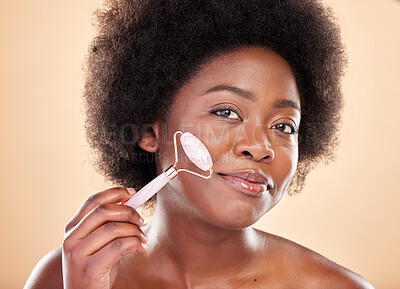 Buy stock photo Black woman, face roller and portrait of beauty, rose quartz cosmetics and natural skincare on studio background. Happy model, facial massage and crystal tools for dermatology of lymphatic drainage