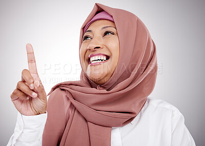 Buy stock photo Muslim, thinking and a woman with an idea in studio for happiness, kindness and positive attitude. Hijab, islam and islamic fashion with a mature person on grey background pointing up at announcement