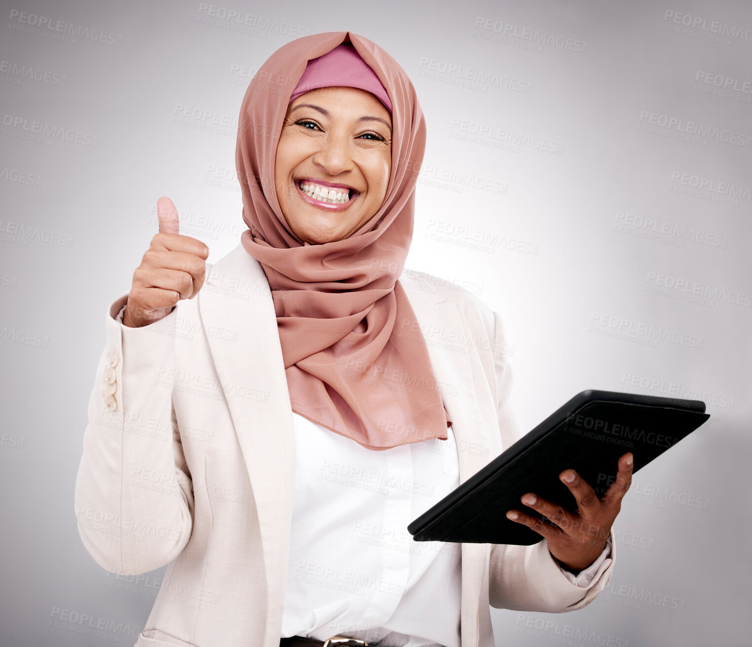 Buy stock photo Thumbs up, tablet and portrait of a muslim woman in a studio doing research on the internet. Happy, smile and mature islamic female model with technology and agreement hand gesture by gray background