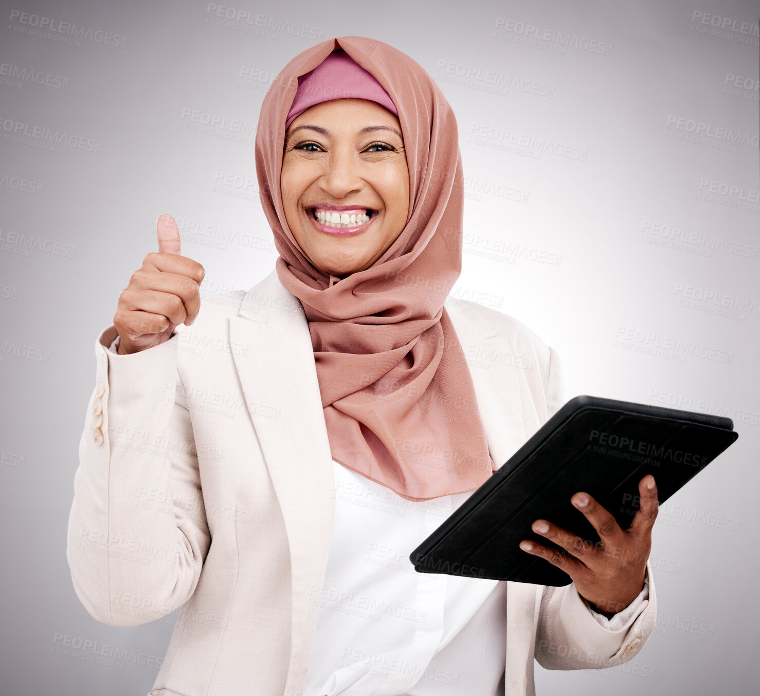 Buy stock photo Thumbs up, tablet and portrait of an islamic woman in studio doing research on the internet. Happy, smile and mature muslim female model with technology and agreement hand gesture by gray background.