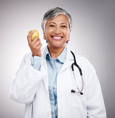 Buy stock photo Doctor, woman and portrait with apple in studio for vitamin c benefits, detox and dietician on gray background. Happy mature nutritionist with fresh fruits for nutrition, healthy food and wellness 